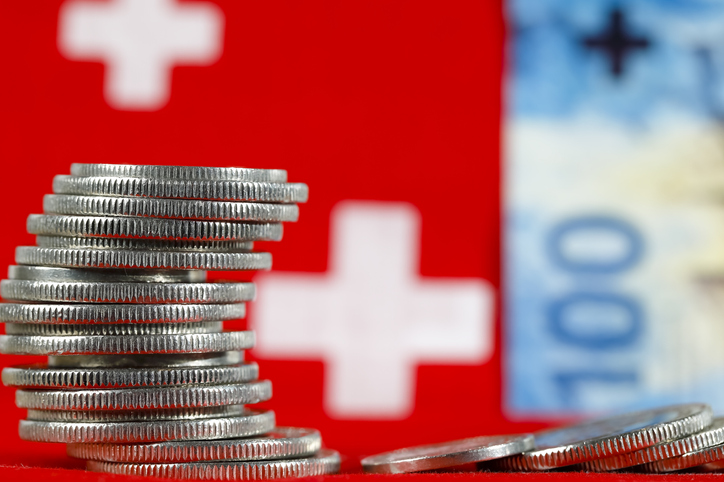 szwajcarskie monety na tle szwajcarskiej flagi